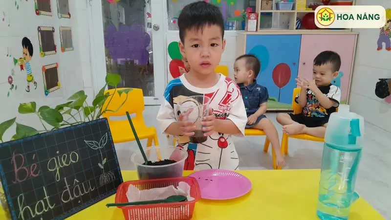 Bé gieo hạt đậu với vật liệu trên bàn tại Hoa Nắng Nhà Bè