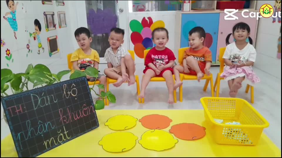 Bé dán mắt, mũi, miệng lên khuôn mặt trong giờ học tại Hoa Nắng Nhà Bè