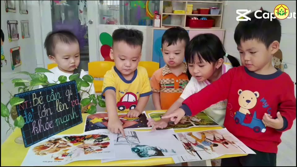 Các bé quan sát tranh trong giờ học bé cần gì để lớn lên khỏe mạnh tại Hoa Nắng Nhà Bè